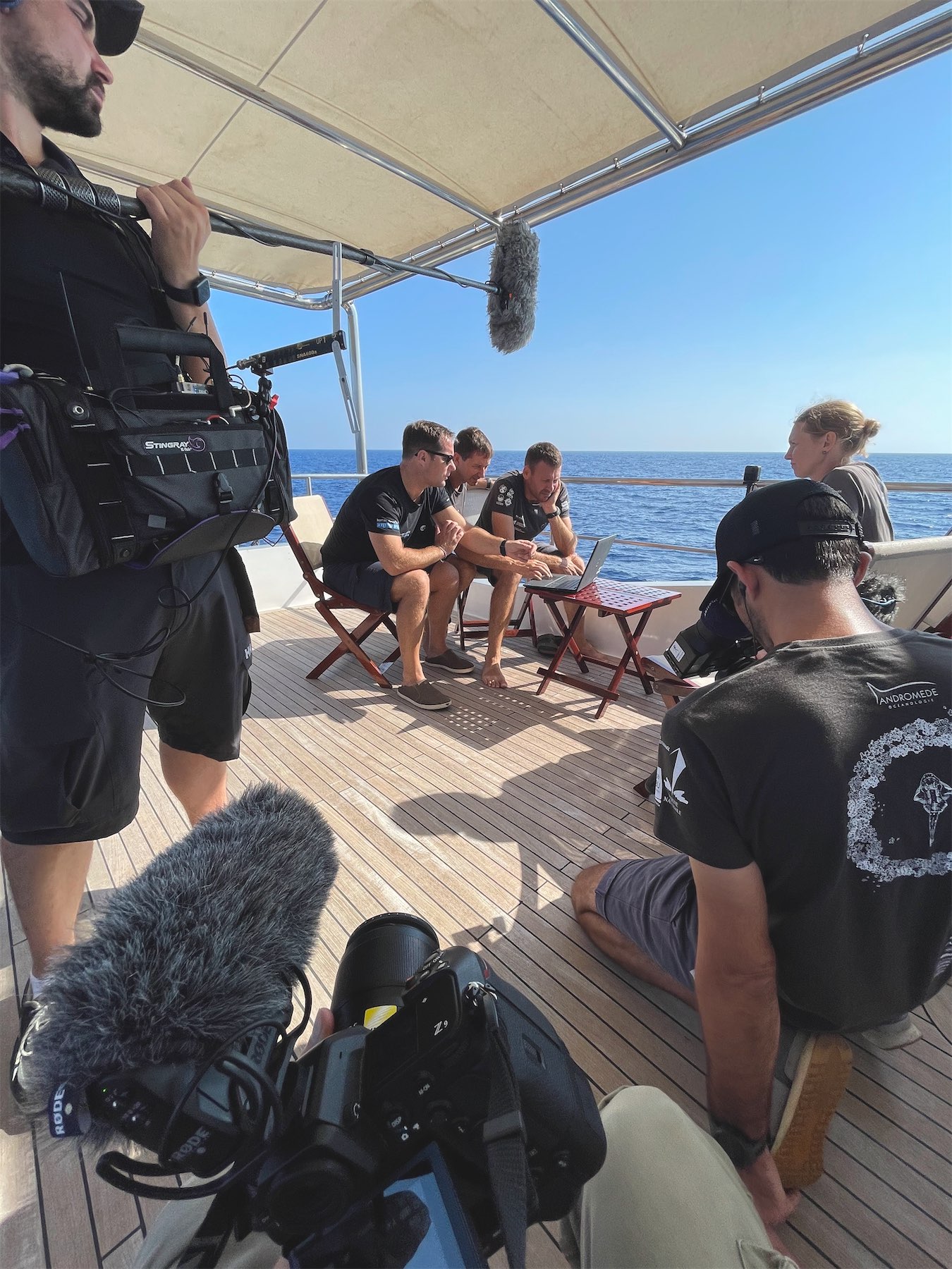 Équipe autour d’un ordinateur sur le pont, avec le matériel de tournage.