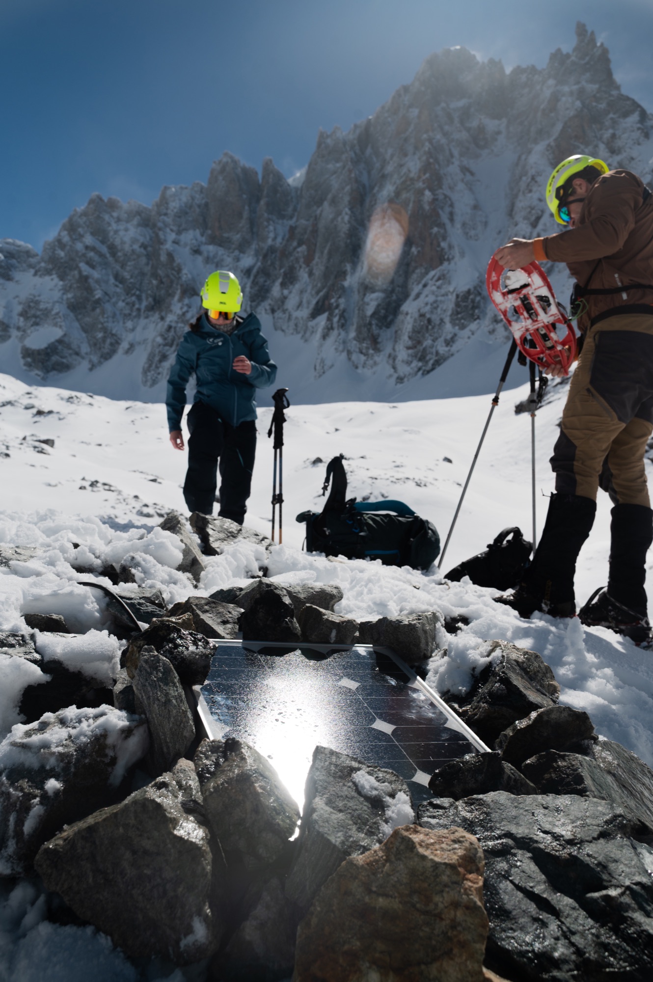 Deux membres de l’équipe équipés de casques, parmi les rochers et la neige.
