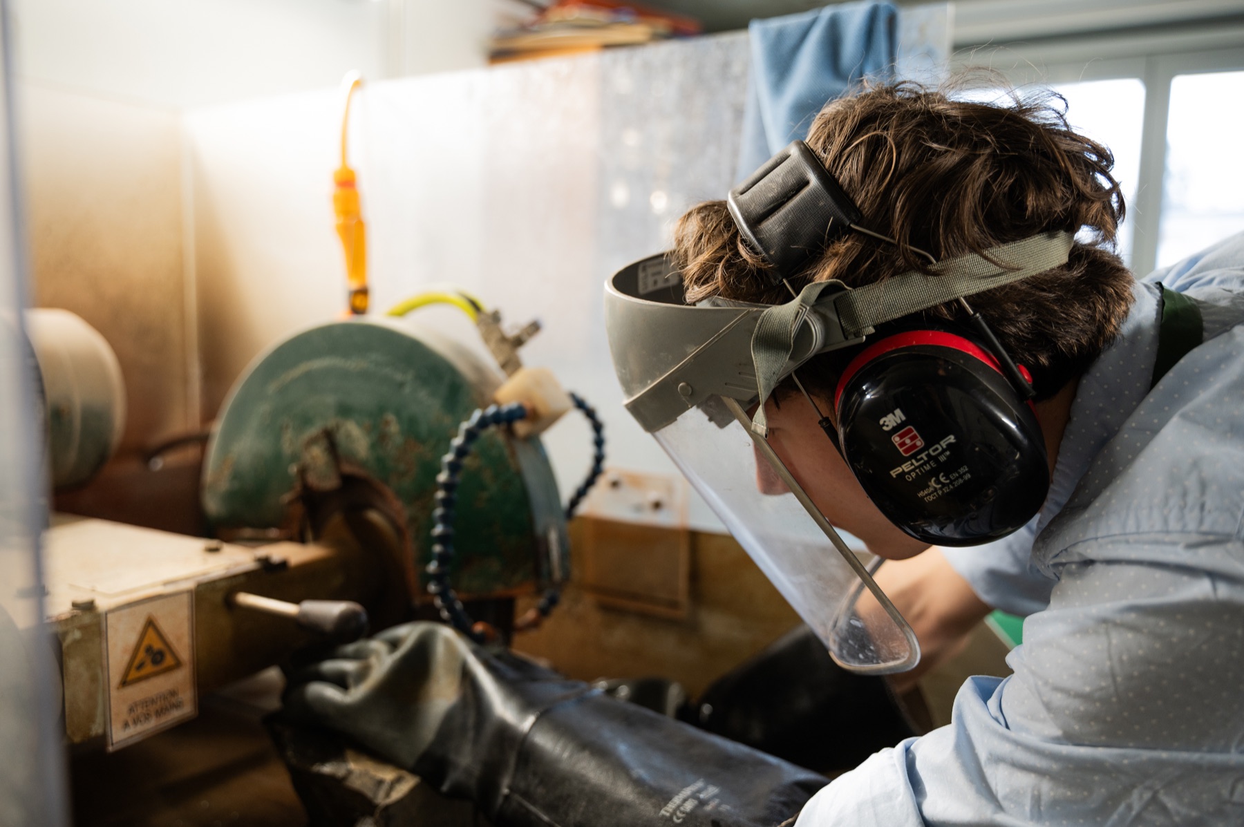 Travail sur un échantillon de roche en atelier, avec un masque de protection.