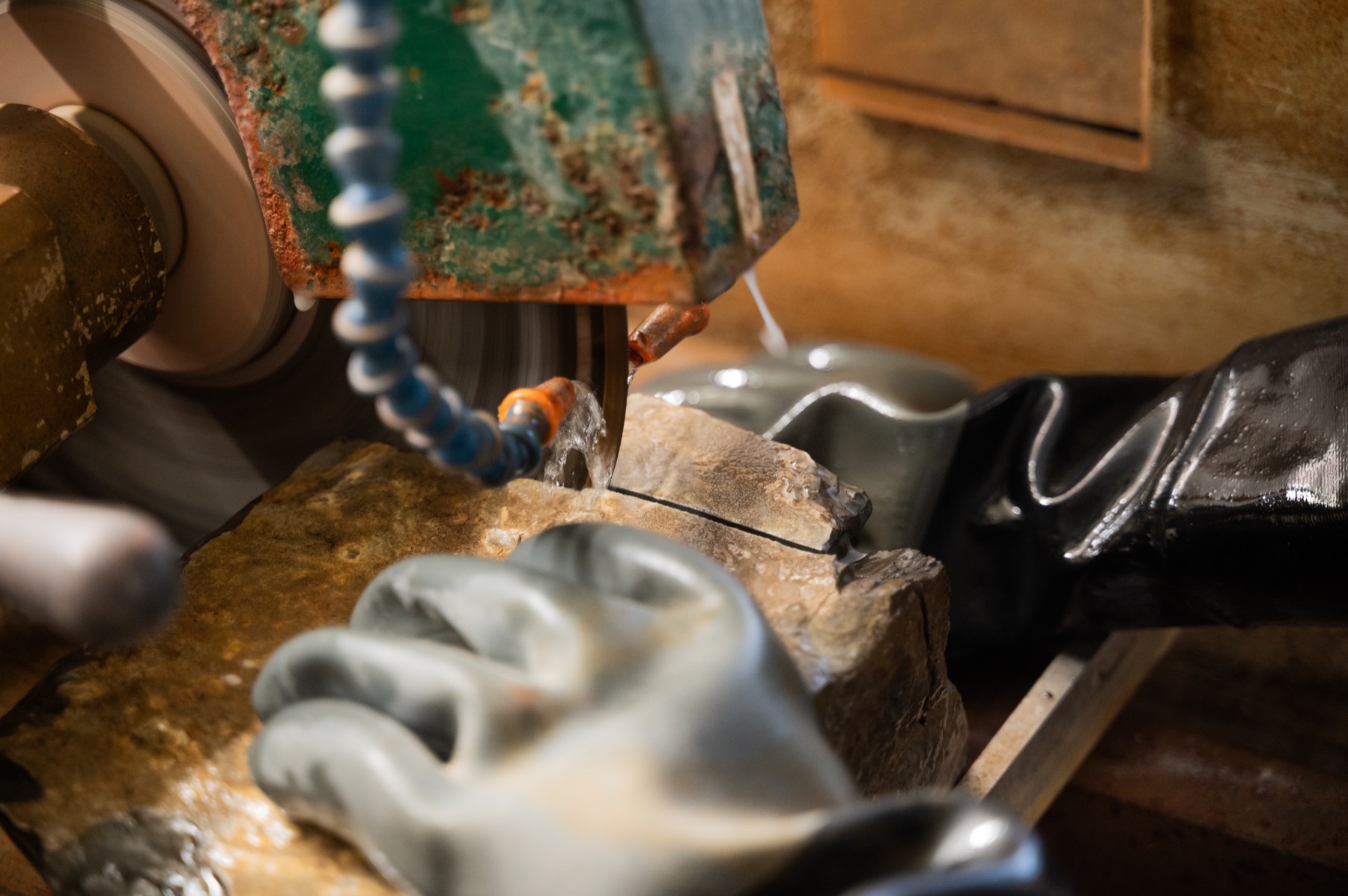 Travail sur la roche sous un outil de découpe, avec des gants de protection.