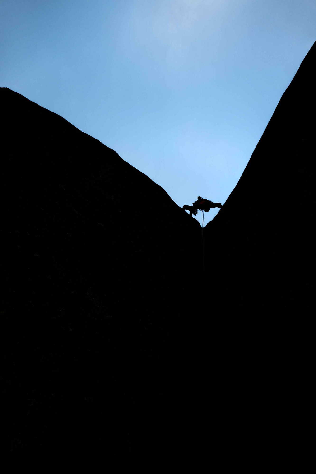 Grimpeur en silhouette entre deux parois.
